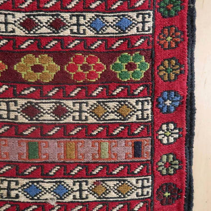 Traditional Azerbaijani Kilim rug with intricate multicolor floral and geometric patterns on red wool, 105×51cm.